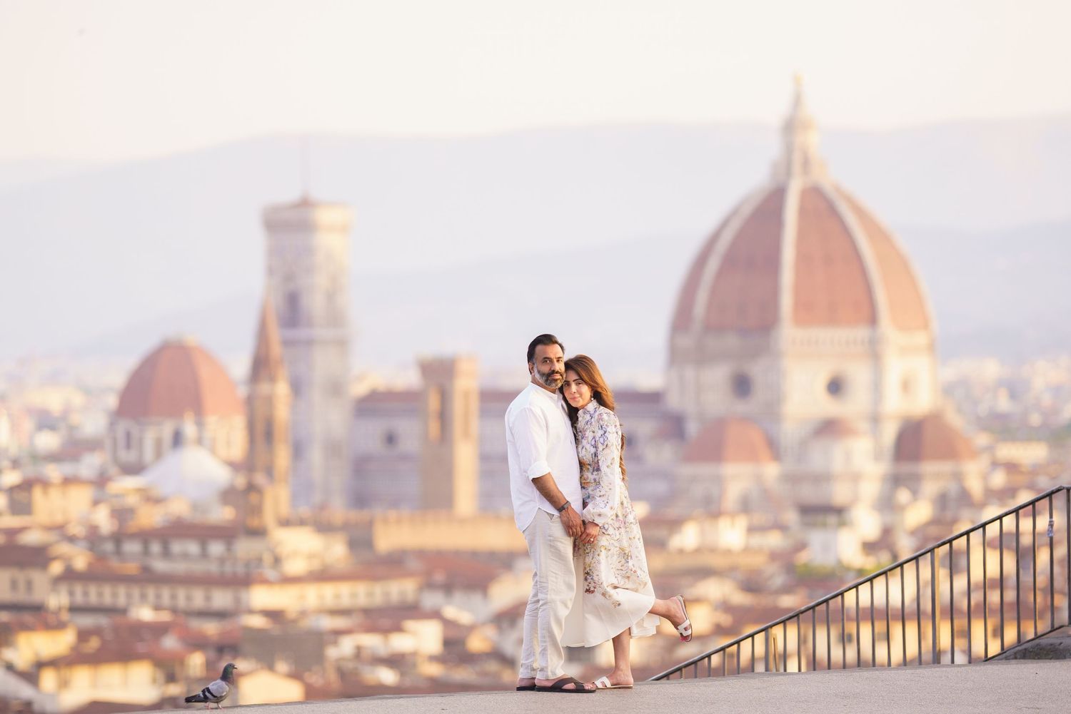 Romantic couple embracing on a terrace overlooking Florence skyline with the iconic Duomo cathedral in the background.