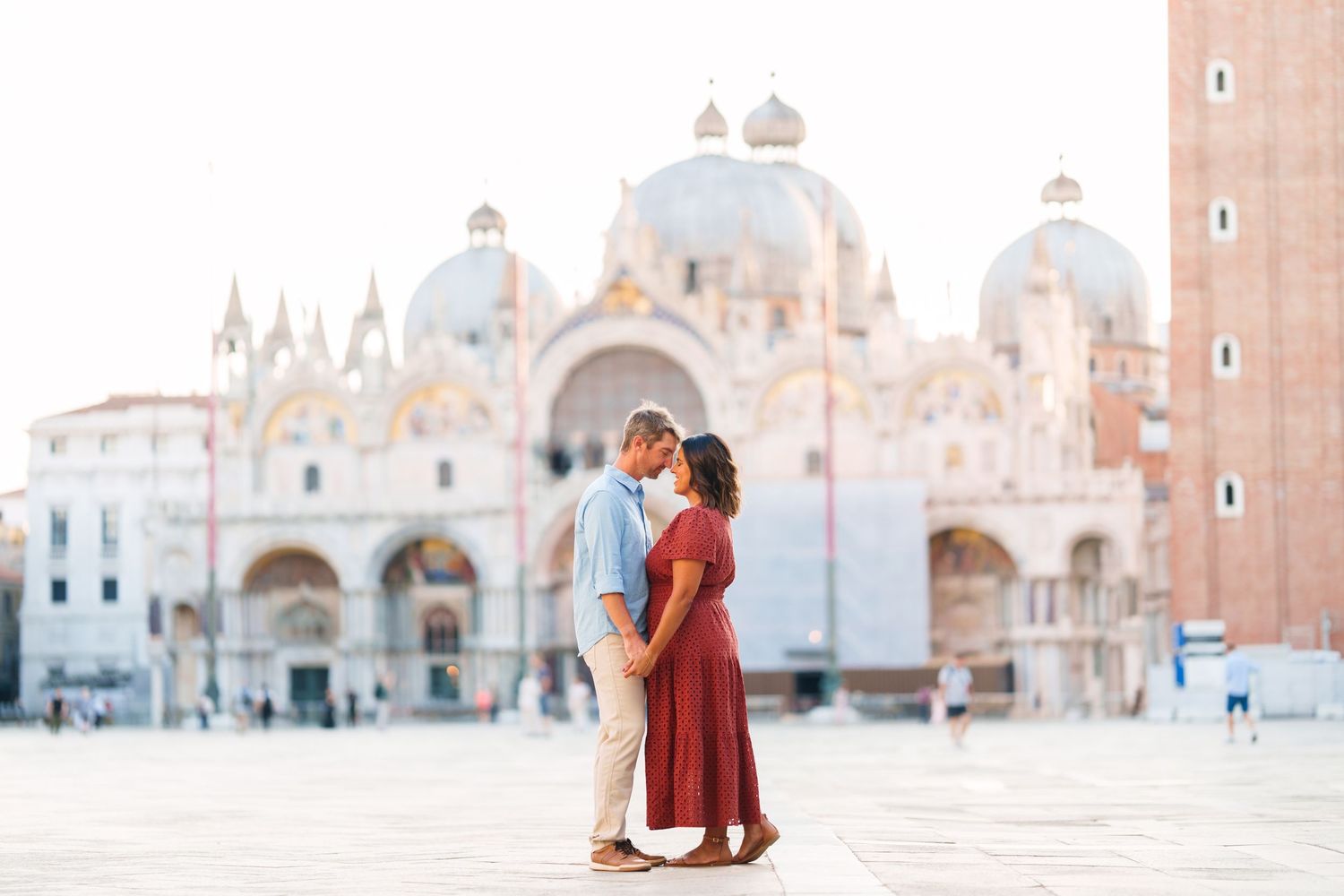 Couple kissing in St. Mark's Square, Venice, with the iconic Basilica di San Marco in the background.