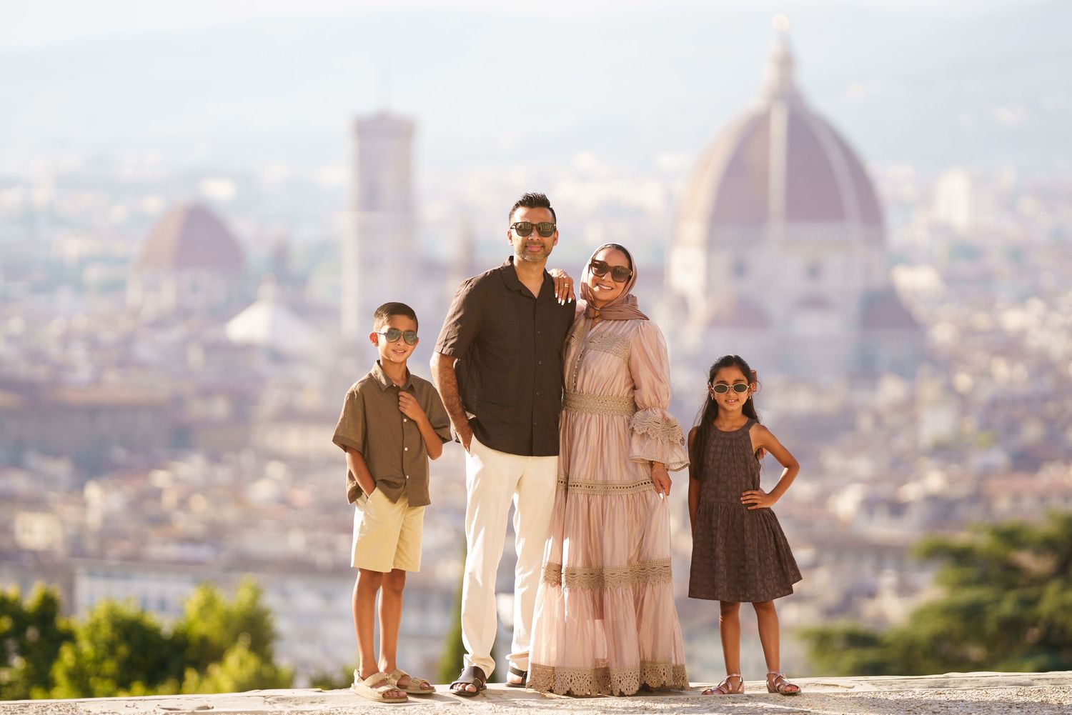 Family of four posing in Florence Italy with the iconic Duomo cathedral visible in the scenic cityscape background.