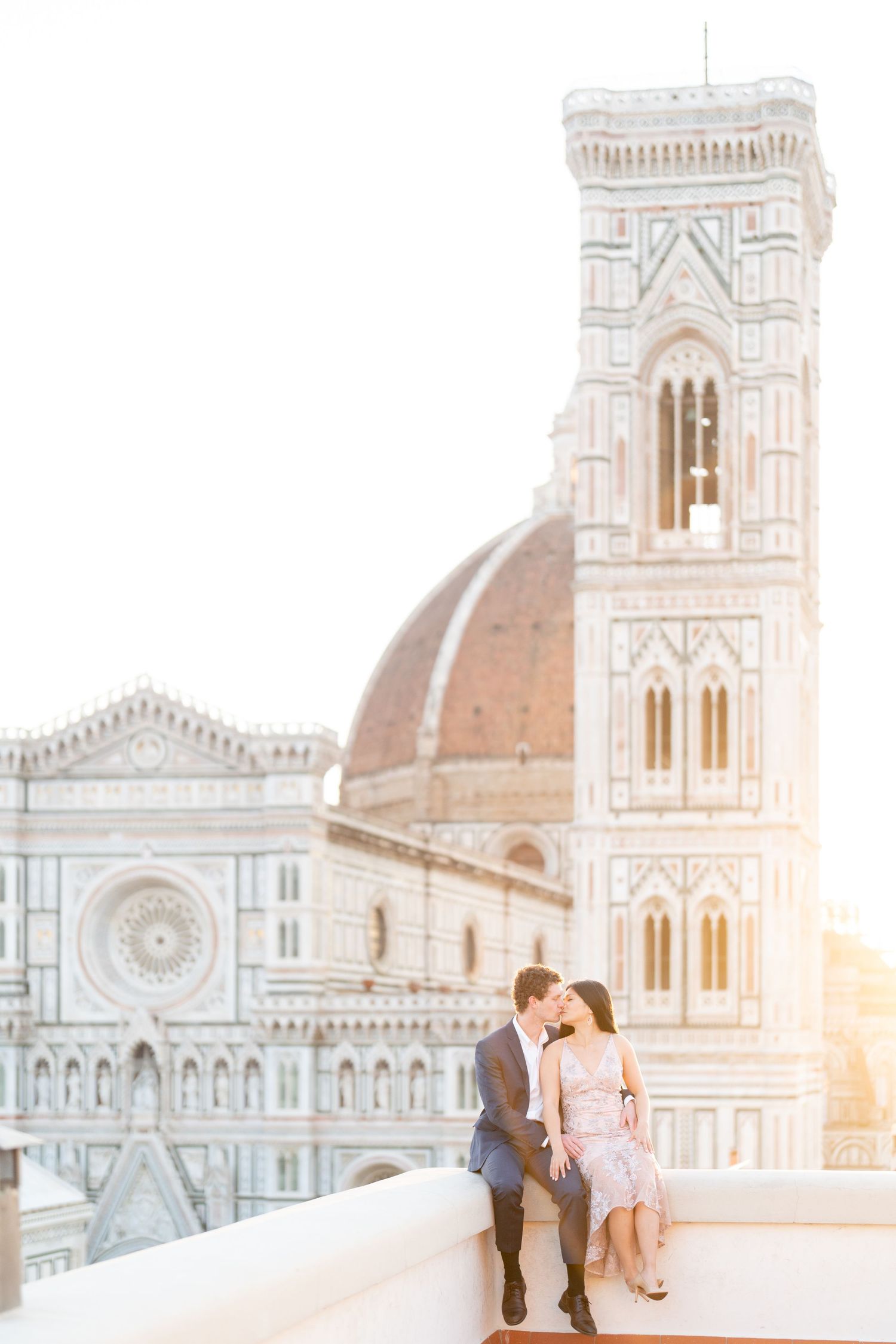A romantic couple shares a tender moment at a viewpoint overlooking the Florence Cathedral during golden hour.