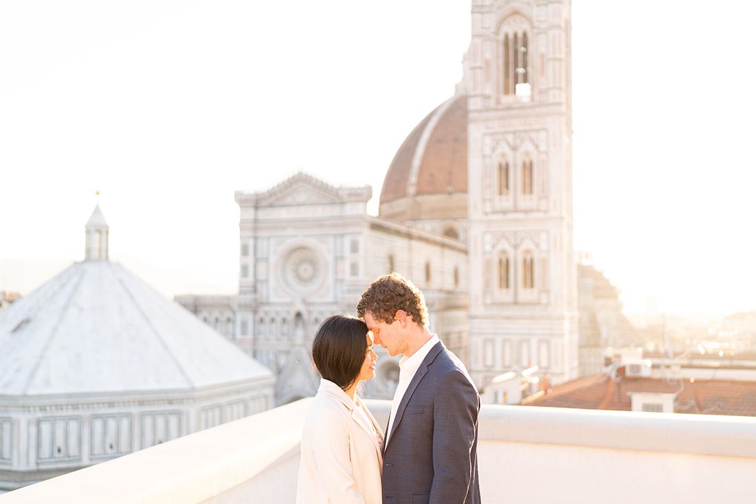 Couple sharing an intimate moment at sunset in front of Florence Cathedral's iconic dome and bell tower in Italy.