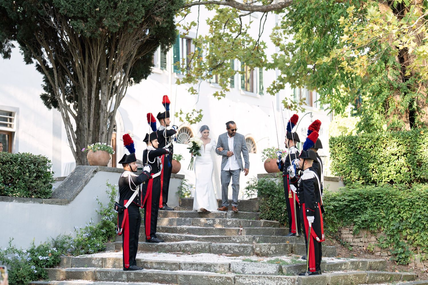 Military officers in ceremonial dress standing at attention on garden steps.