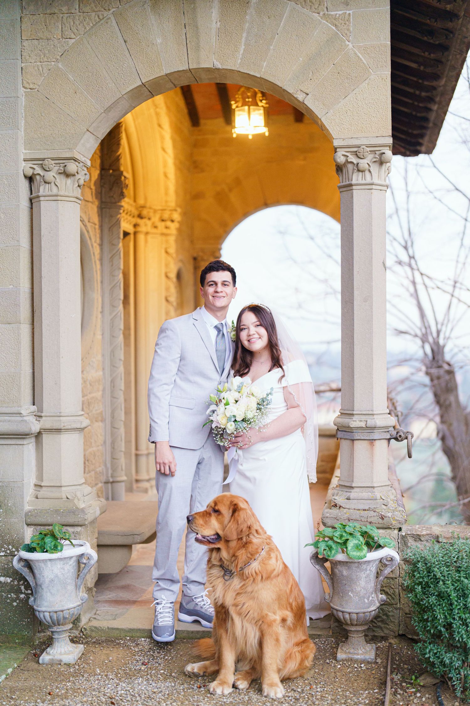Stone colonnade with arched walkway featuring couple and their golden retriever in formal portraits.