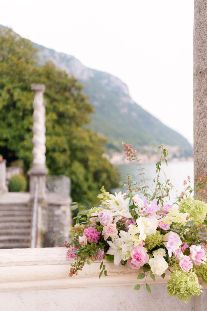 Elegant floral arrangements with pink and white blooms decorating a stone terrace with mountain views.