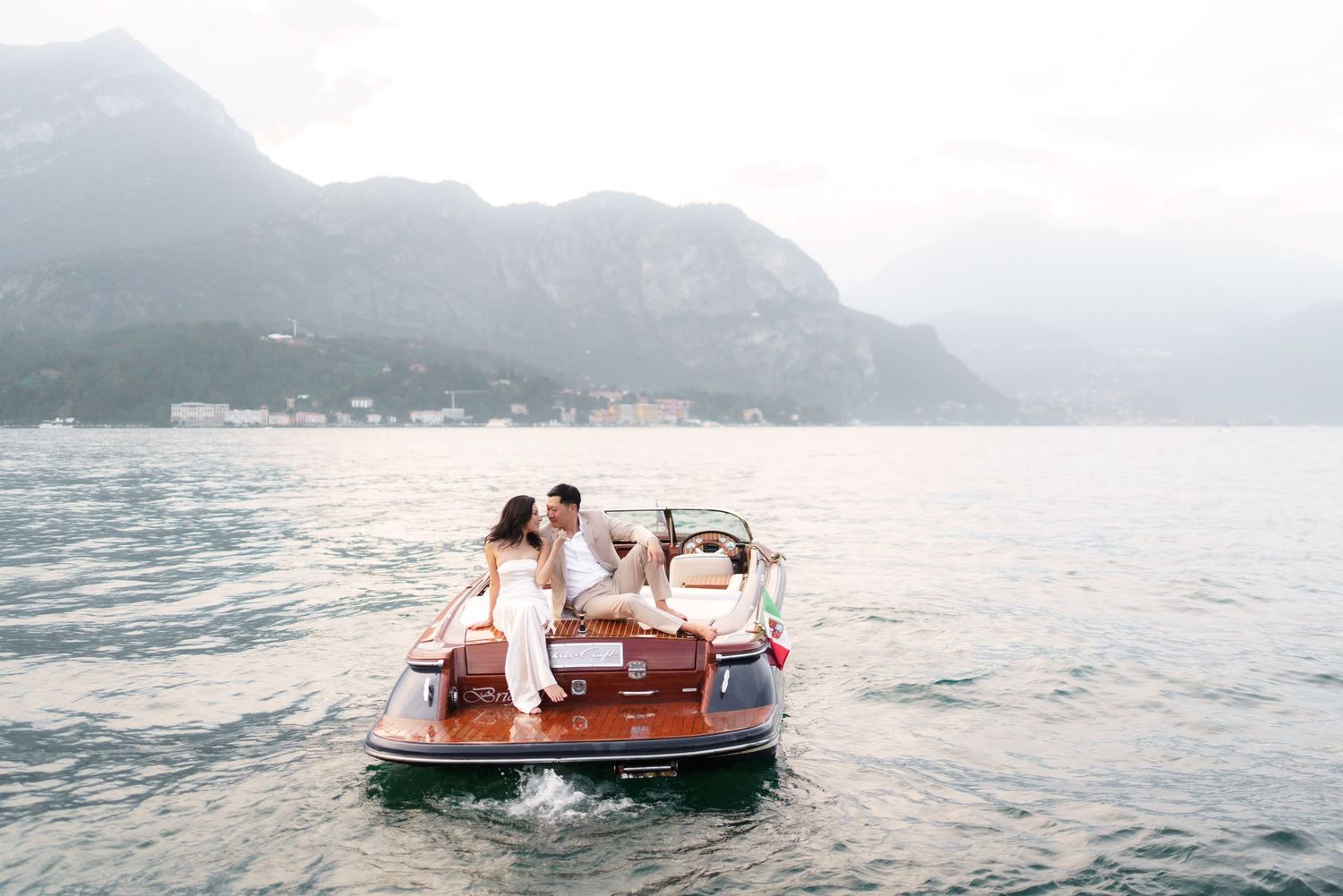 A boat journey across a misty lake with mountains in the background during a serene summer day.
