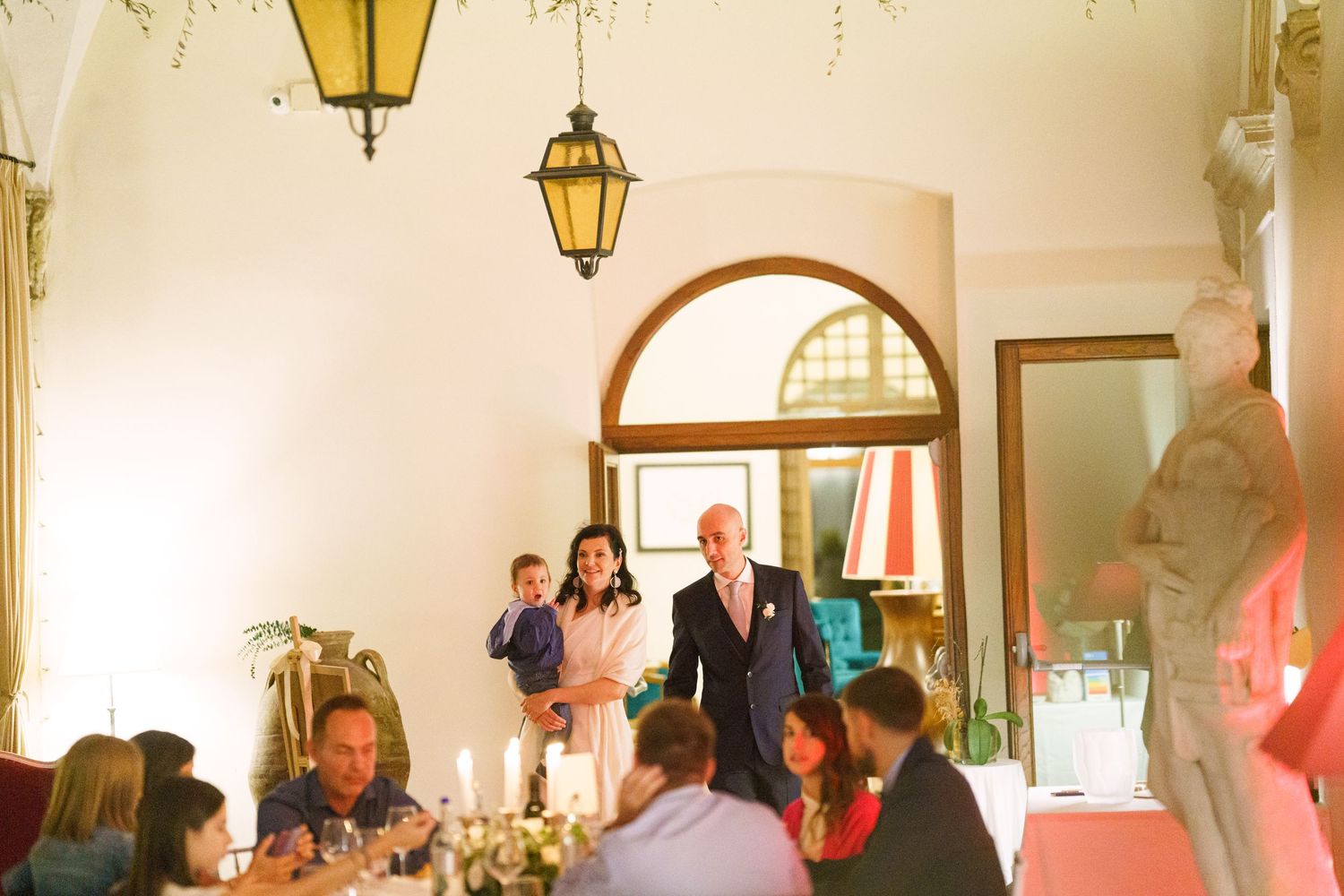 Yellow lantern illuminates an elegant reception venue with white walls and arched doorways.