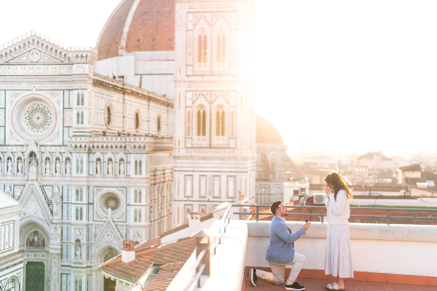A couple shares a romantic moment on a rooftop terrace overlooking Florence Cathedral during golden hour sunset.