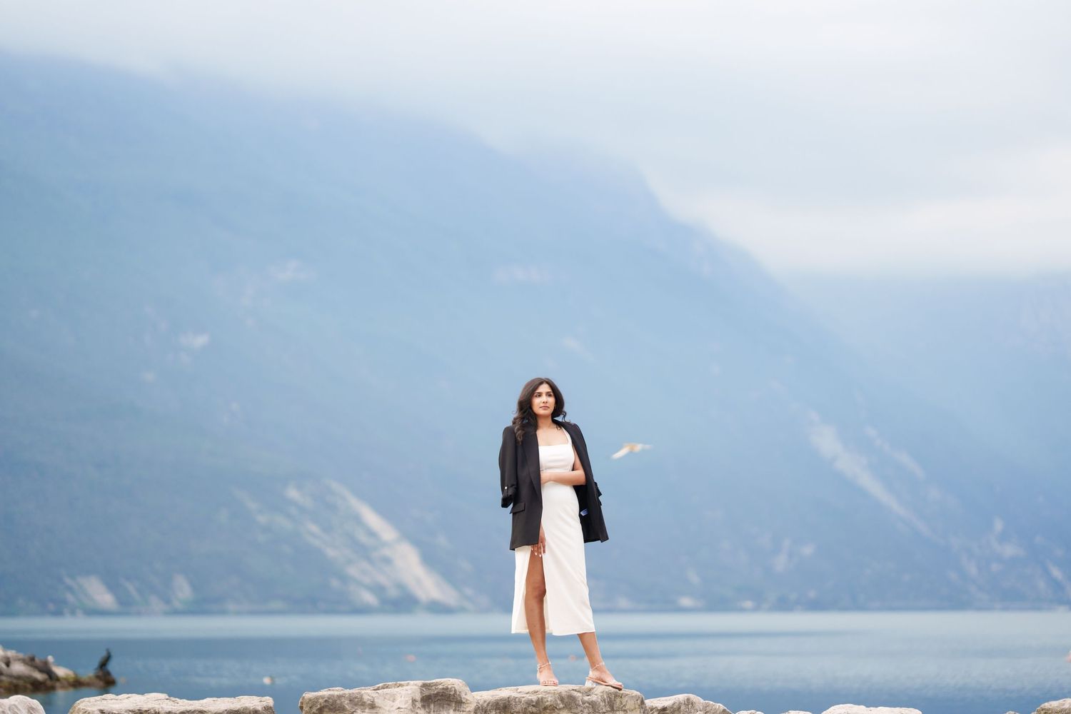 A couple stands at the edge of a scenic mountain lake overlook on a misty day.