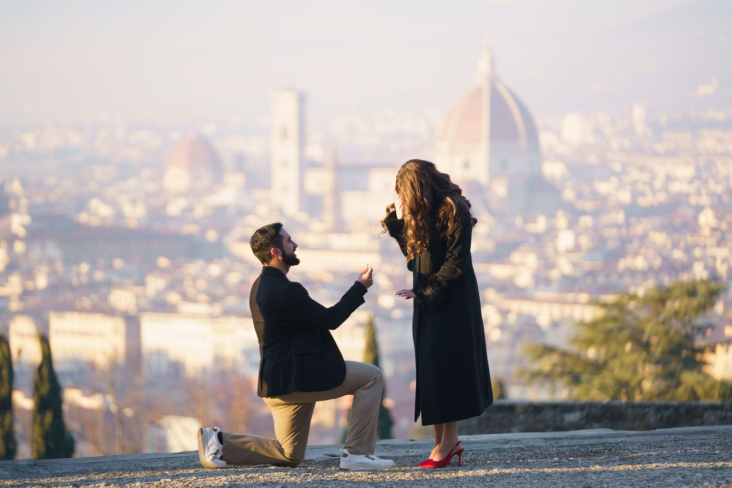 A romantic proposal moment overlooking Florence, Italy with the iconic Duomo cathedral visible in the misty cityscape.