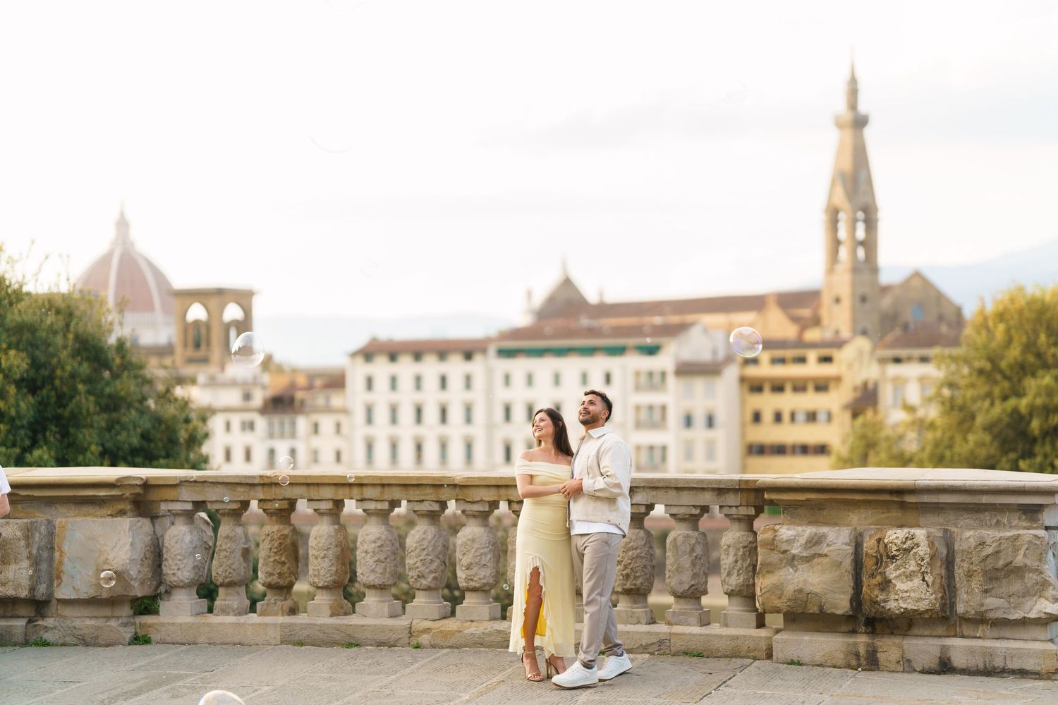 Couple embracing on a terrace in Florence, Italy, with the iconic Duomo and historic buildings in the background.