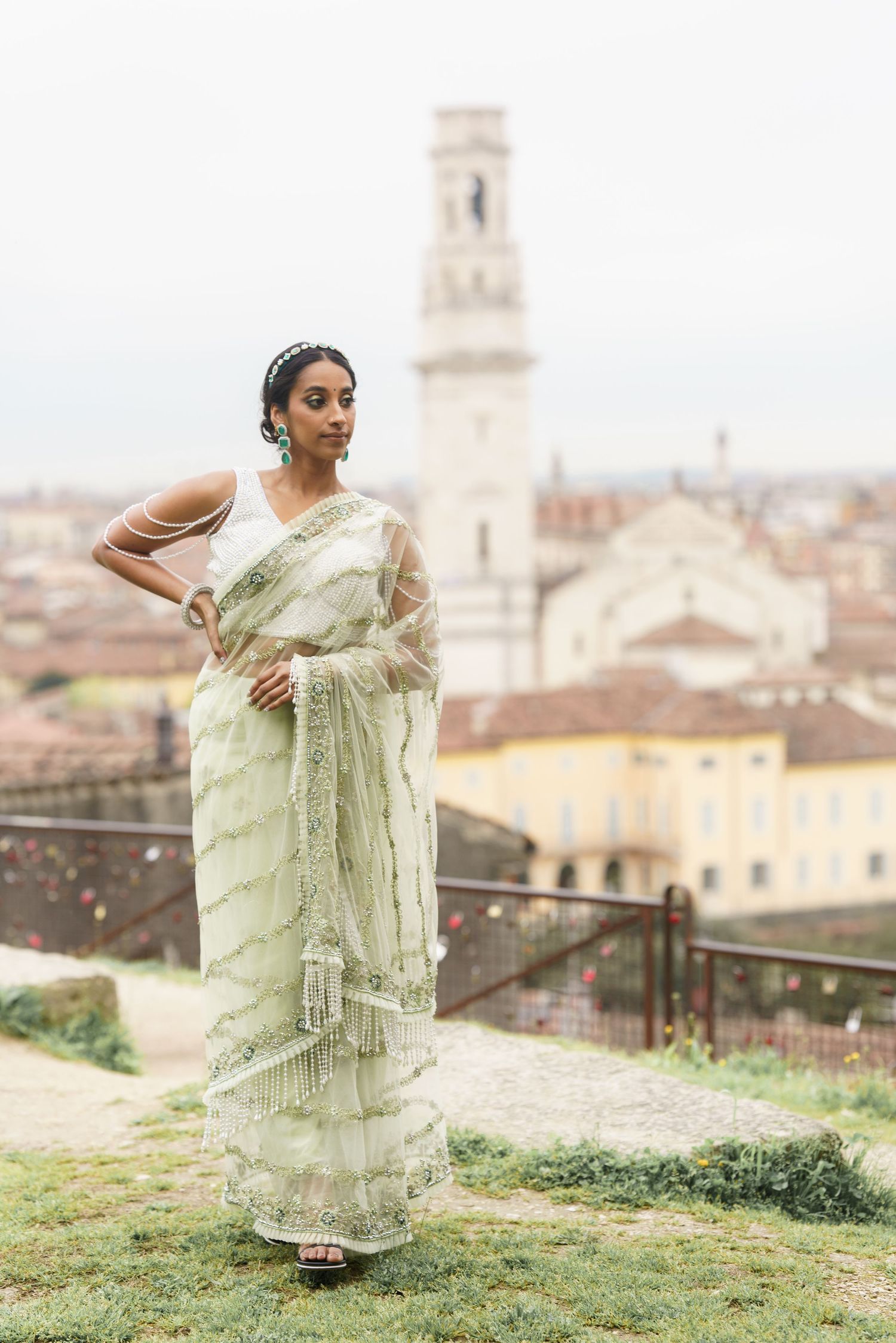 Woman in traditional mint green saree poses gracefully against scenic Italian cityscape backdrop in Florence.
