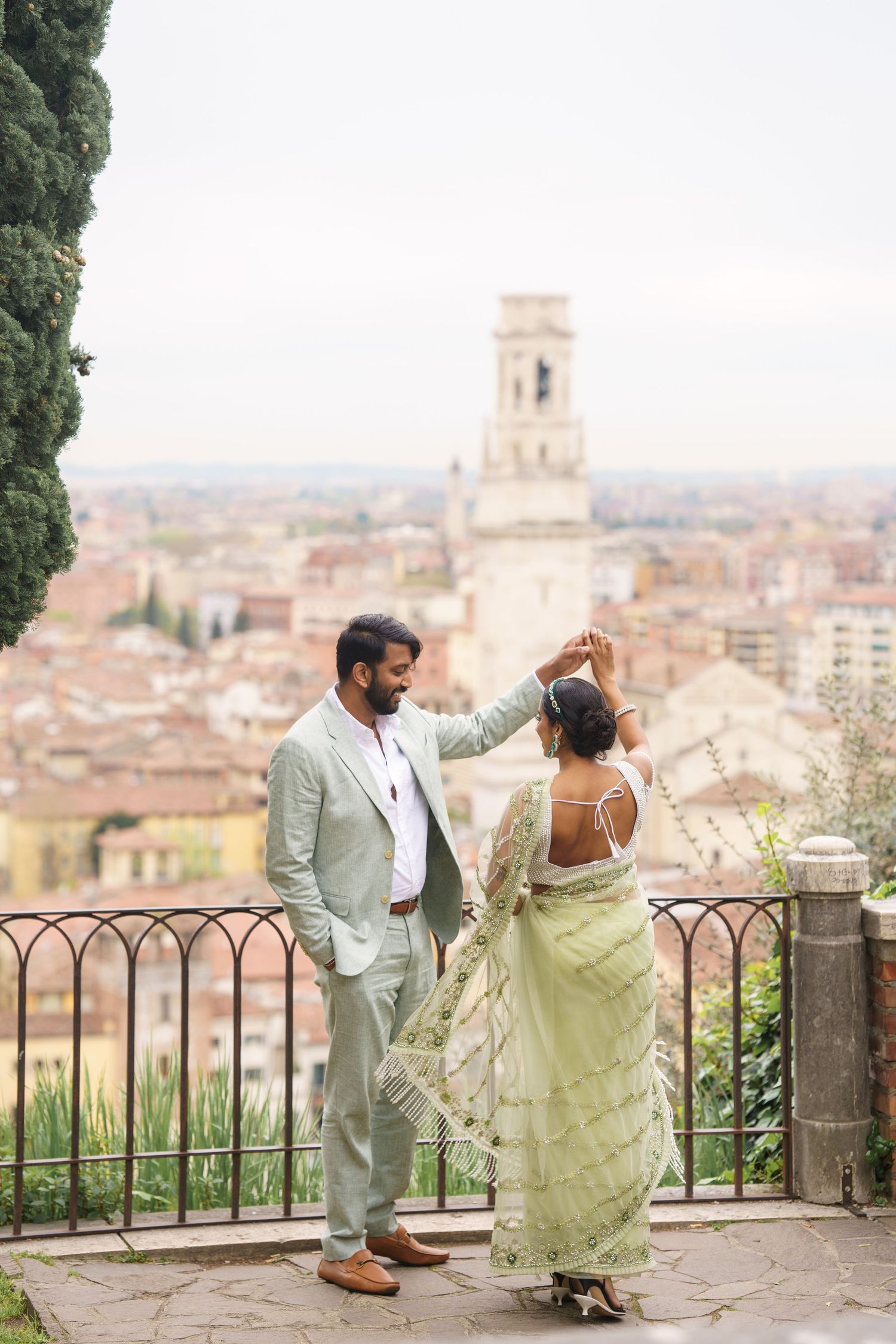 Couple enjoying a romantic moment overlooking the historic city of Florence from a scenic viewpoint with iron railings.