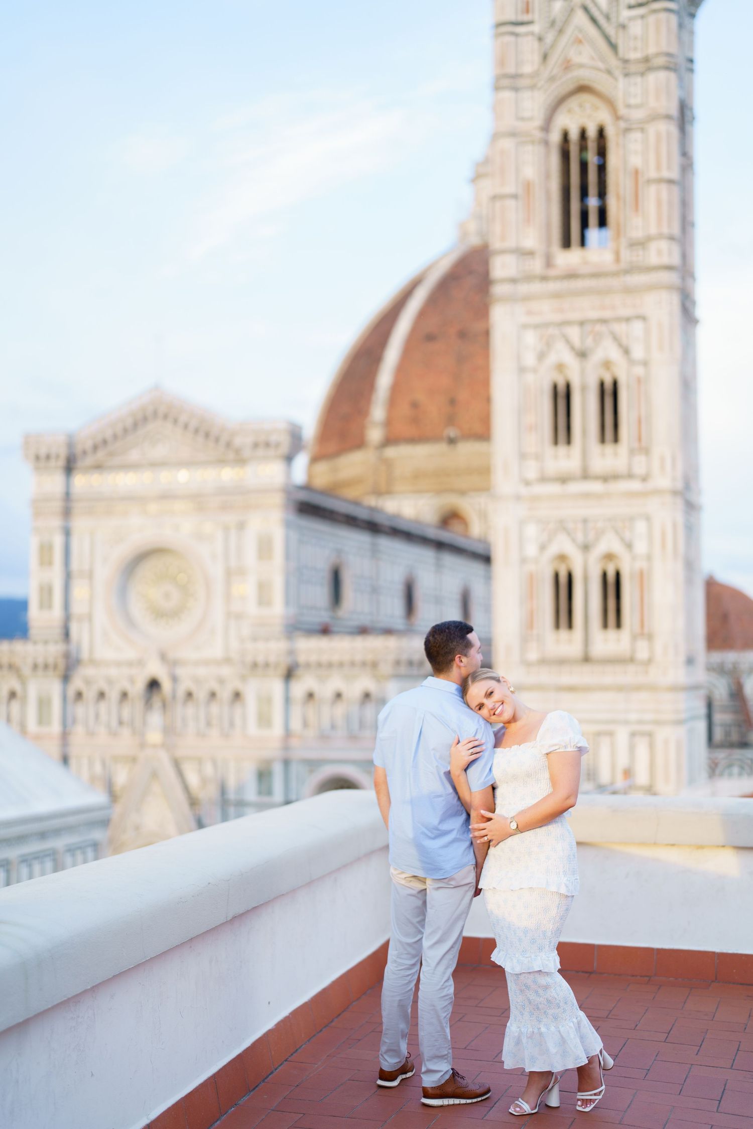 A couple shares a romantic moment on a terrace overlooking the historic Florence Cathedral in Italy.