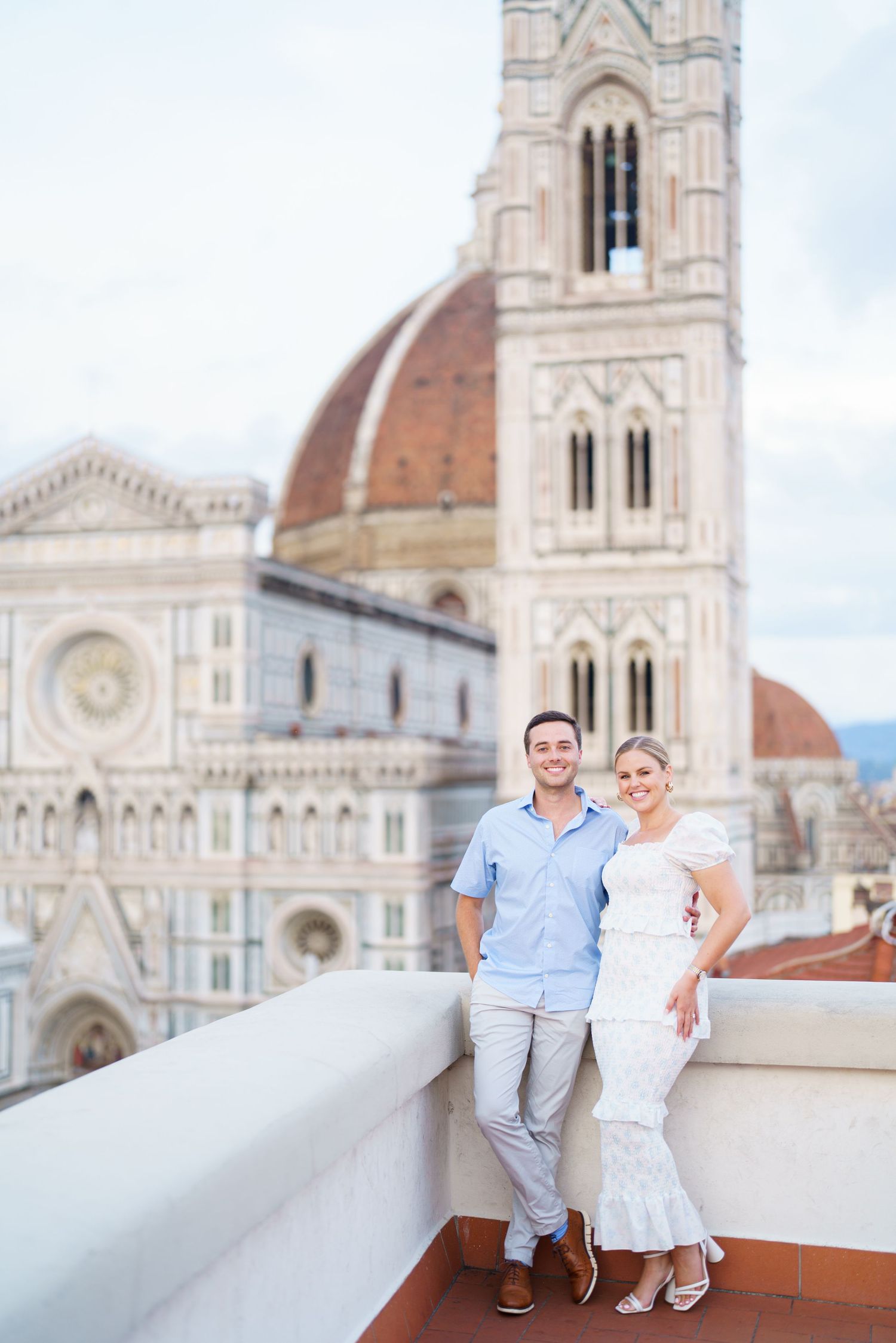 Couple posing together on a rooftop terrace with Florence Cathedral and Duomo in the background.
