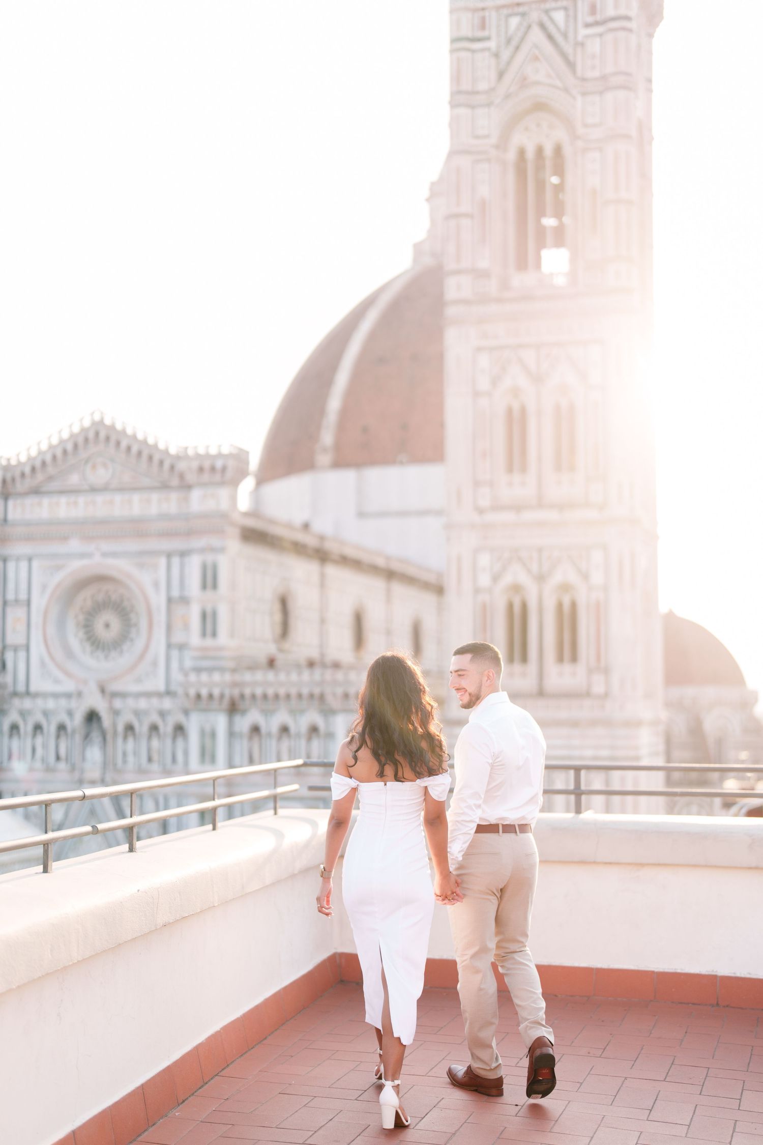A romantic couple shares a tender moment on a rooftop terrace with a beautiful cathedral and sunset backdrop in Zagreb.