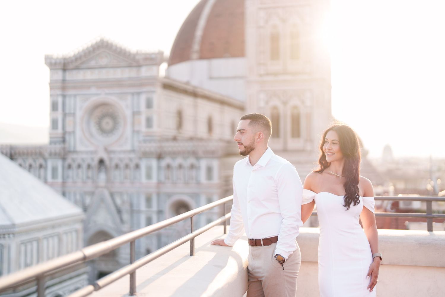 A couple shares a romantic moment during sunset in Florence, Italy with the Duomo cathedral in the background.