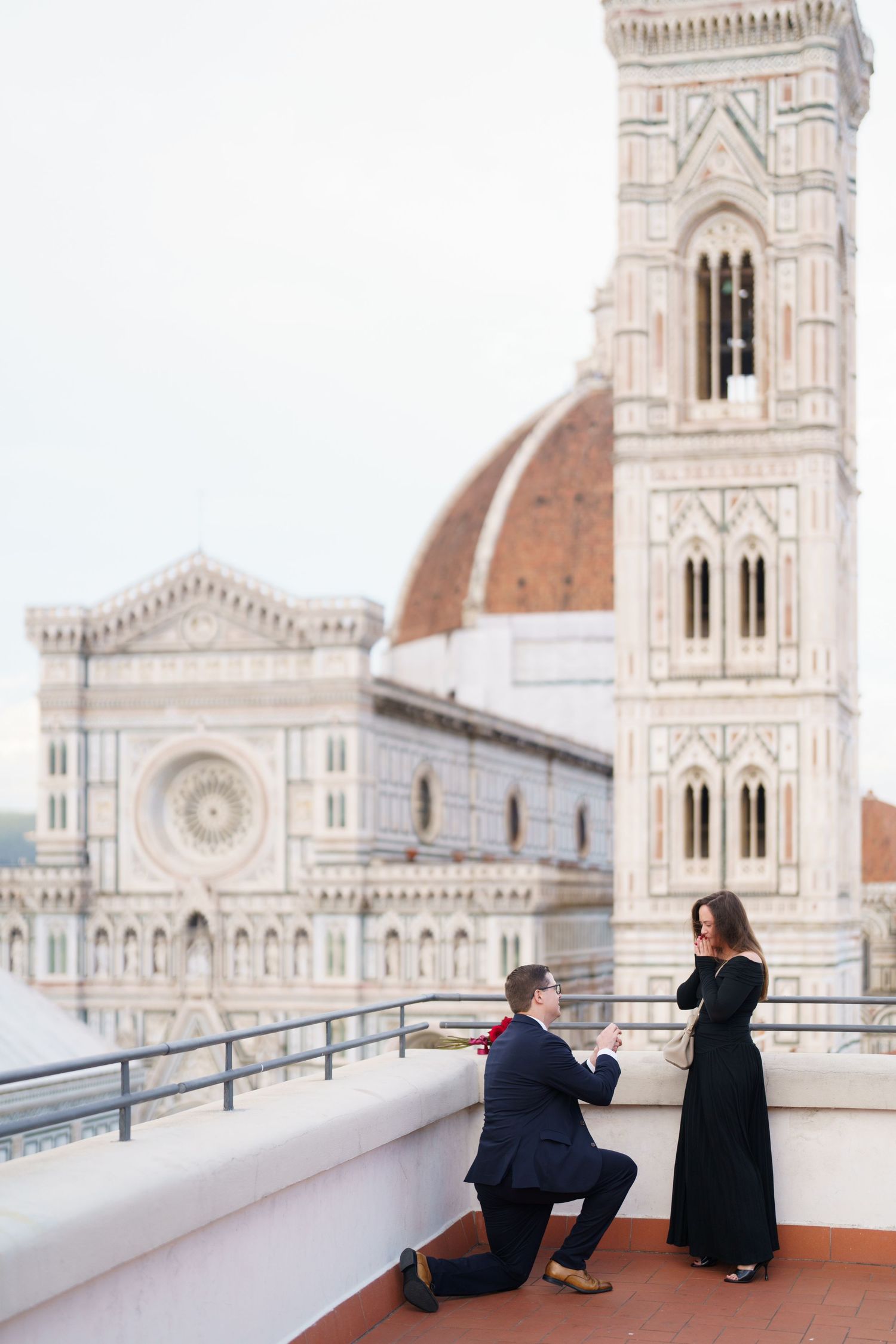Couple sits on rooftop terrace overlooking Florence Cathedral's iconic dome and architectural details in Italy.