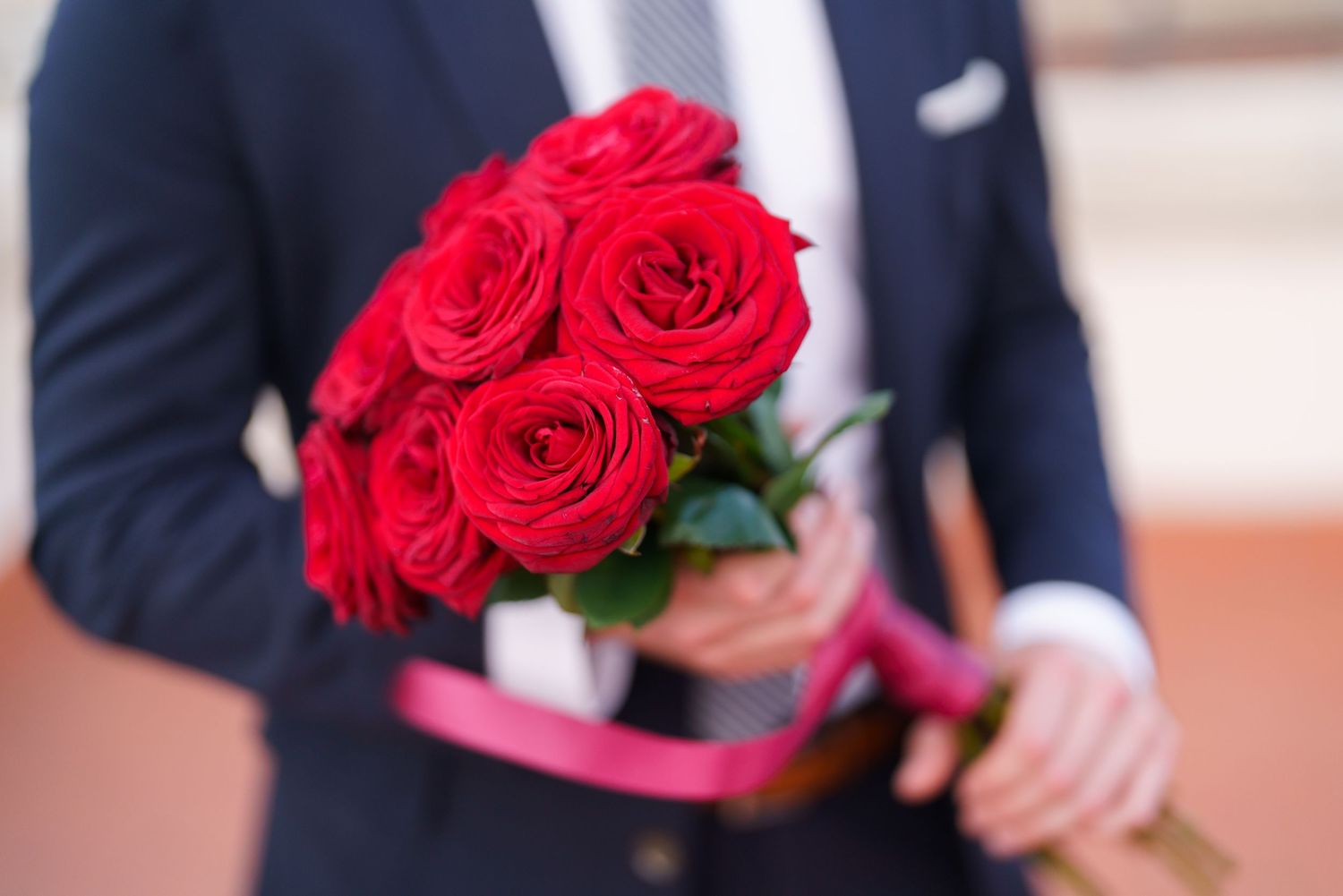 Red roses are held against a blurred background of Florence's historic architecture and skyline.