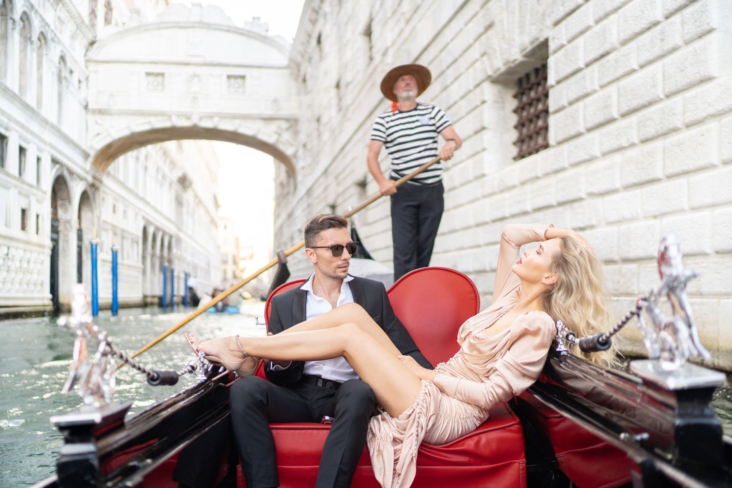 Tourists enjoy a romantic gondola ride through the scenic canals of Venice, Italy during a sunny afternoon.