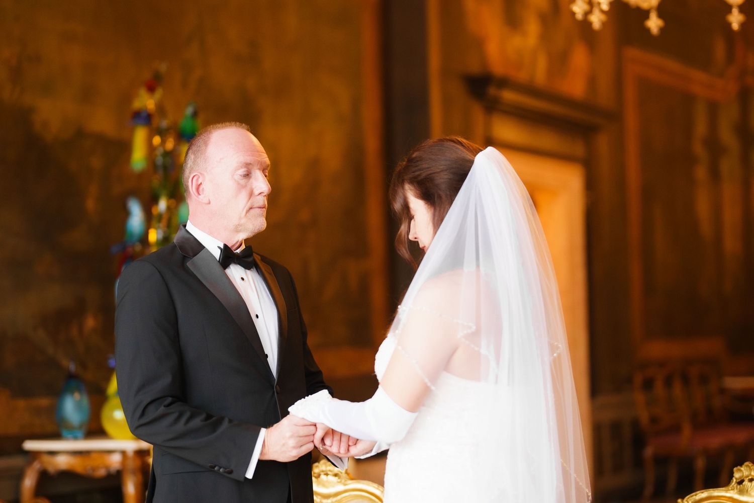 A bride and groom sign their marriage certificate during an elegant indoor wedding ceremony.