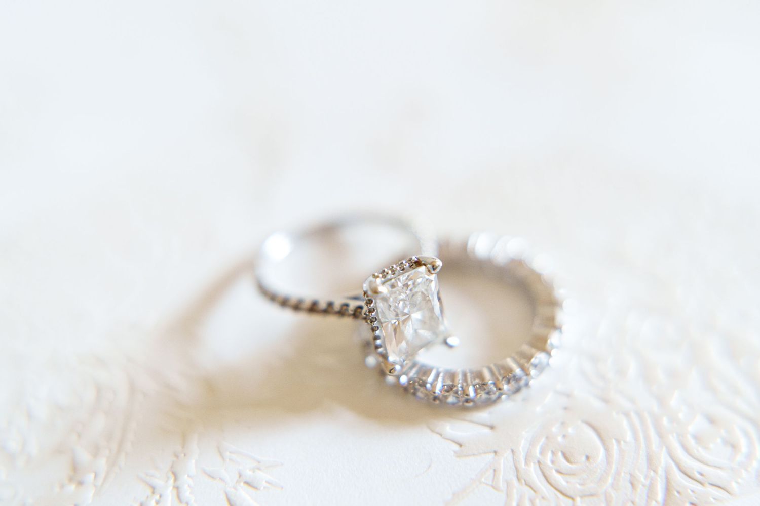 Sparkling diamond wedding rings displayed on delicate white lace fabric.