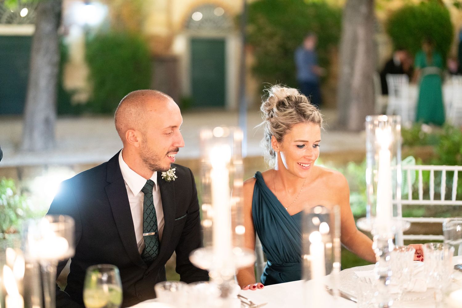 Guests seated at candlelit tables during an elegant outdoor wedding reception.