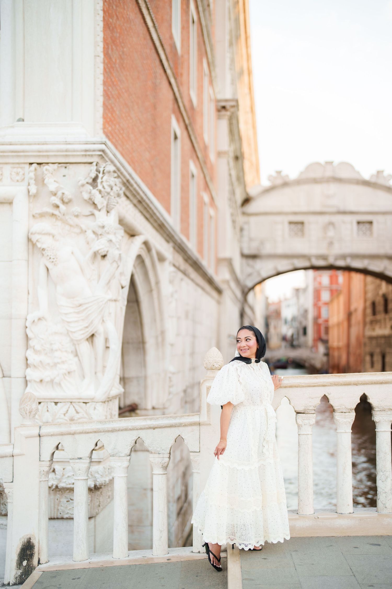 Woman in white dress posing near the Bridge of Sighs in Venice, Italy.