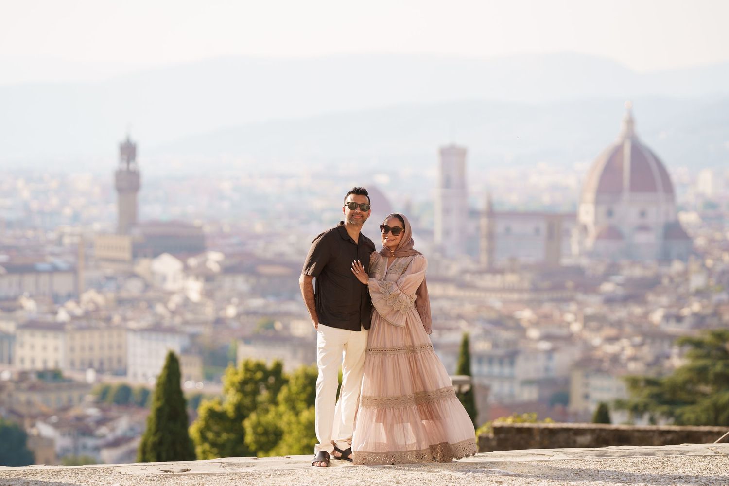 Couple posing with Florence skyline featuring the Duomo and Palazzo Vecchio in the background.