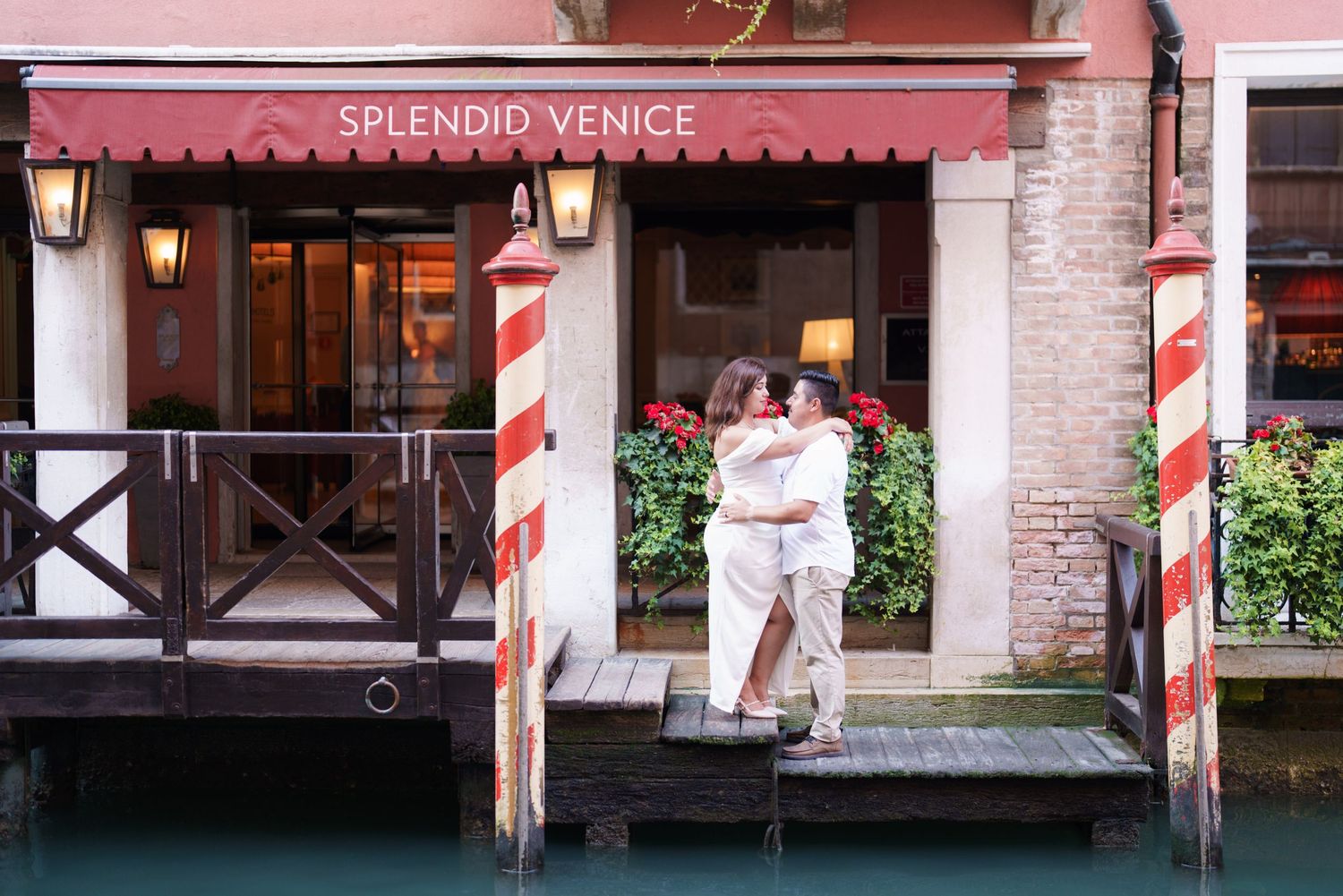 Splendido Venice restaurant entrance with red and white striped poles along a canal in Venice, Italy.
