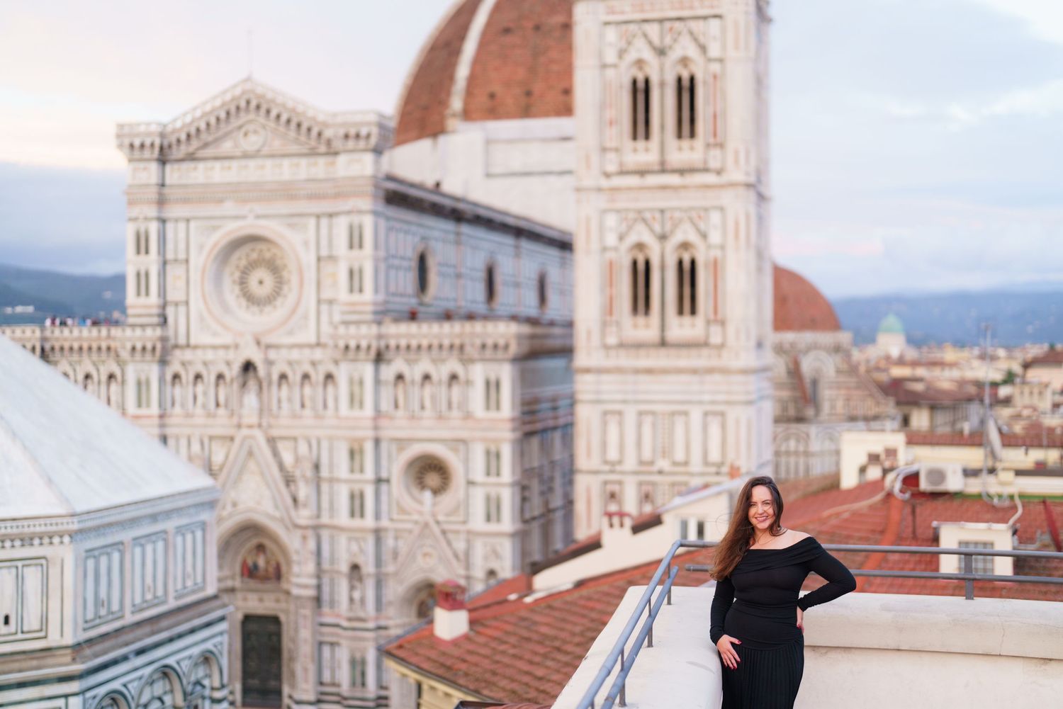 Tourist poses on rooftop terrace overlooking the historic Florence Cathedral and Duomo in Italy.