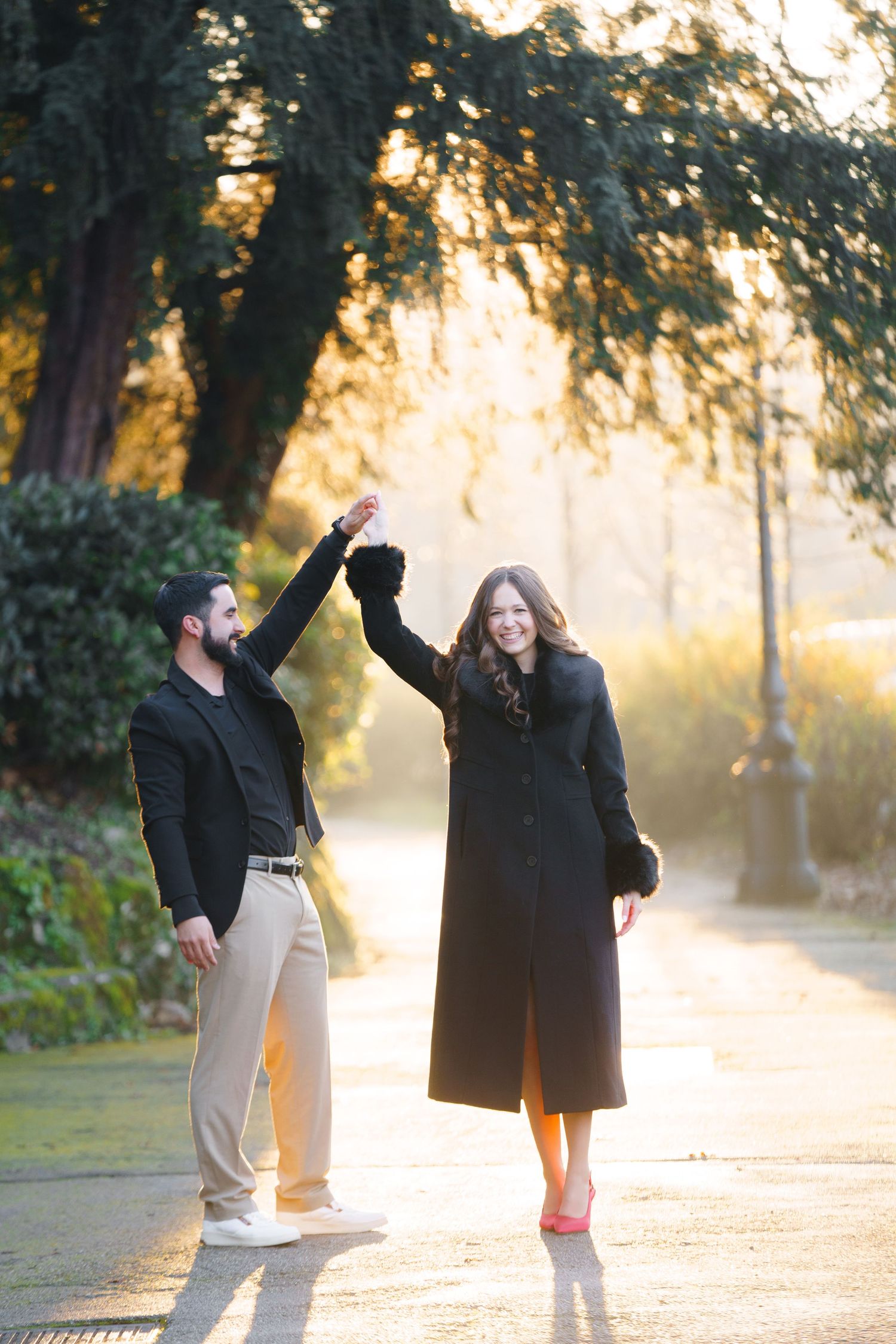 A couple dancing together on a misty path during golden hour sunset with trees in the background.