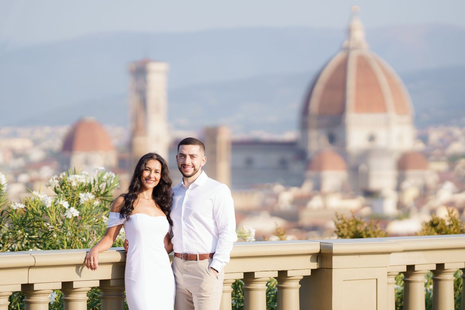 Romantic couple poses against the scenic backdrop of Florence, Italy with the iconic Duomo cathedral visible in the distance.
