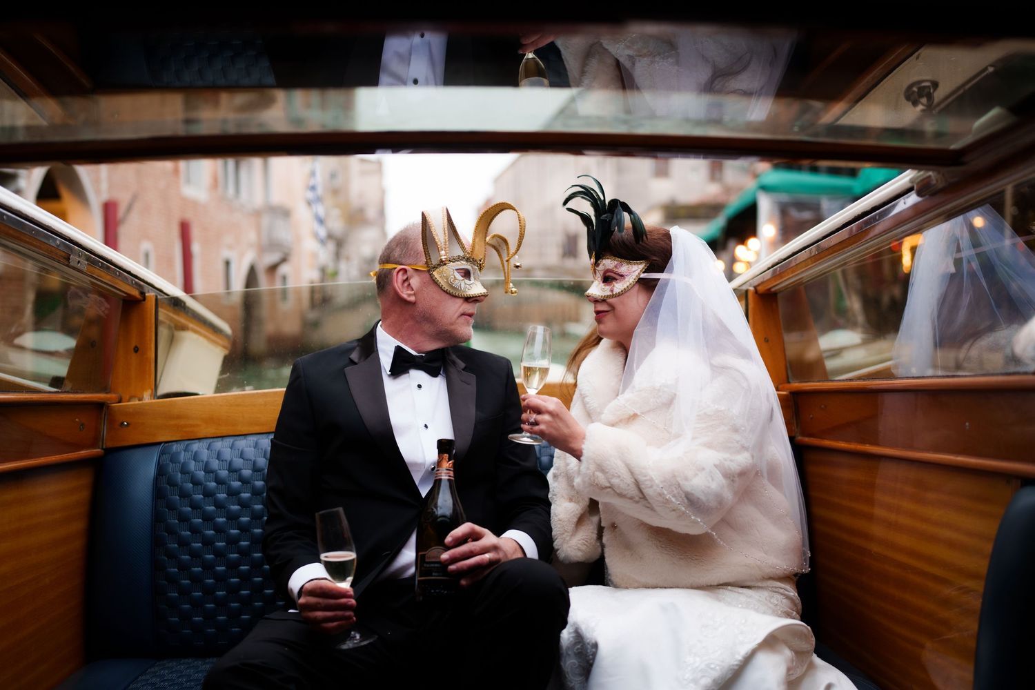 Newlywed couple sits together in a wooden boat during their romantic wedding celebration on the water.