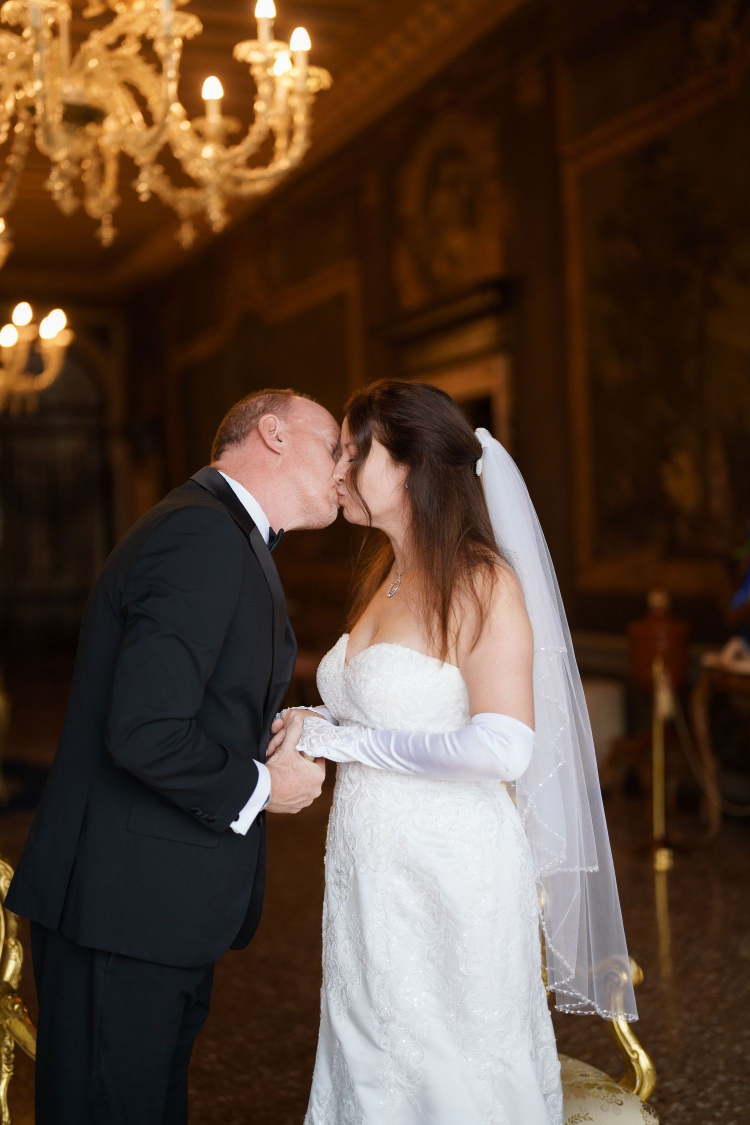 A romantic wedding kiss sequence showing three progressive moments between a couple in an ornate ballroom with chandeliers.