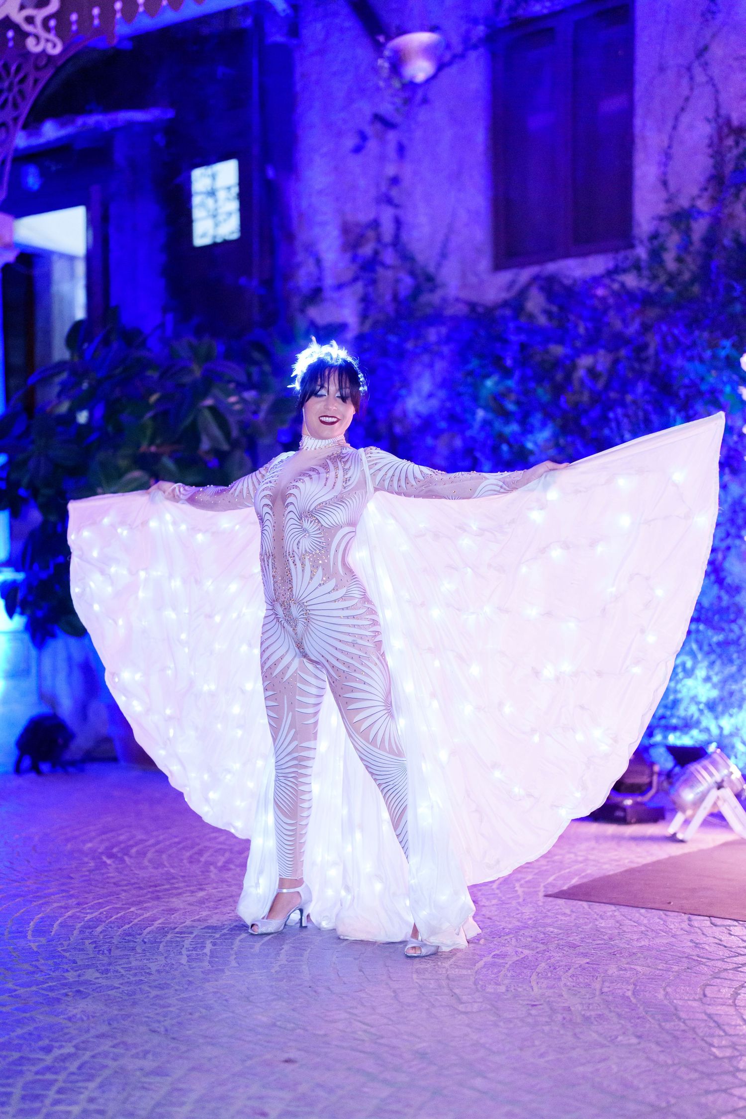 Ethereal white dress performance on cobblestone floor with dramatic blue backlighting.