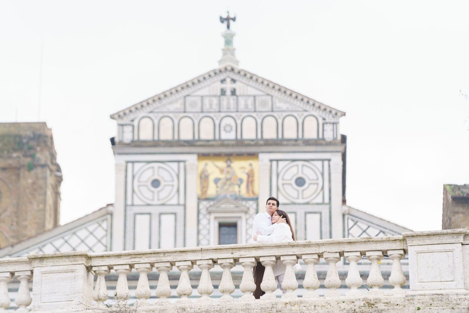 Couple sharing tender moment on historic church balcony in Florence.