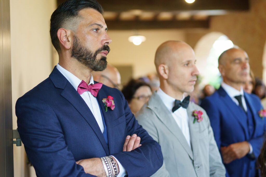Guests in formal attire seated at a wedding ceremony in an elegant indoor venue.