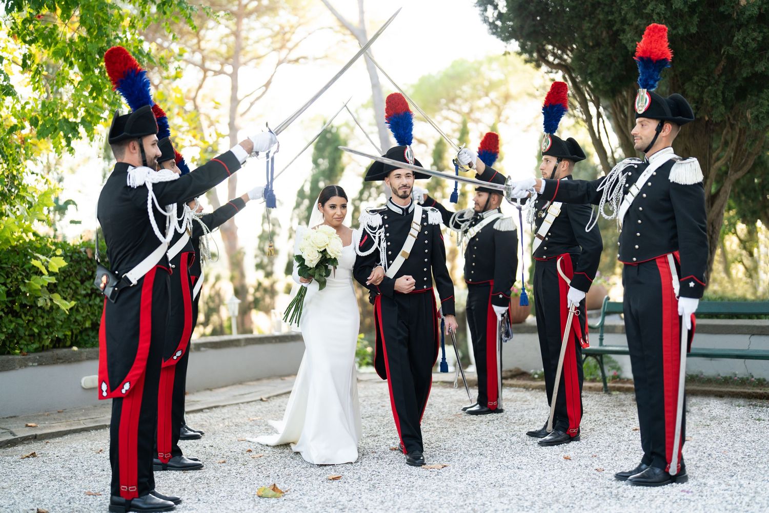 Military honor guard forms line during outdoor wedding ceremony on gravel path.