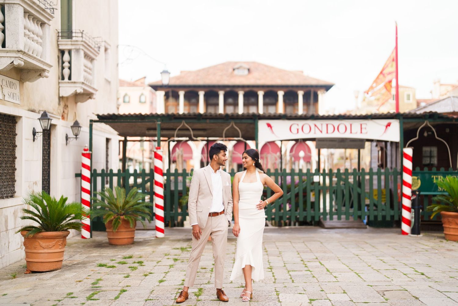 A series of balconies and terraces with red and white striped poles line the exterior of a historic building.