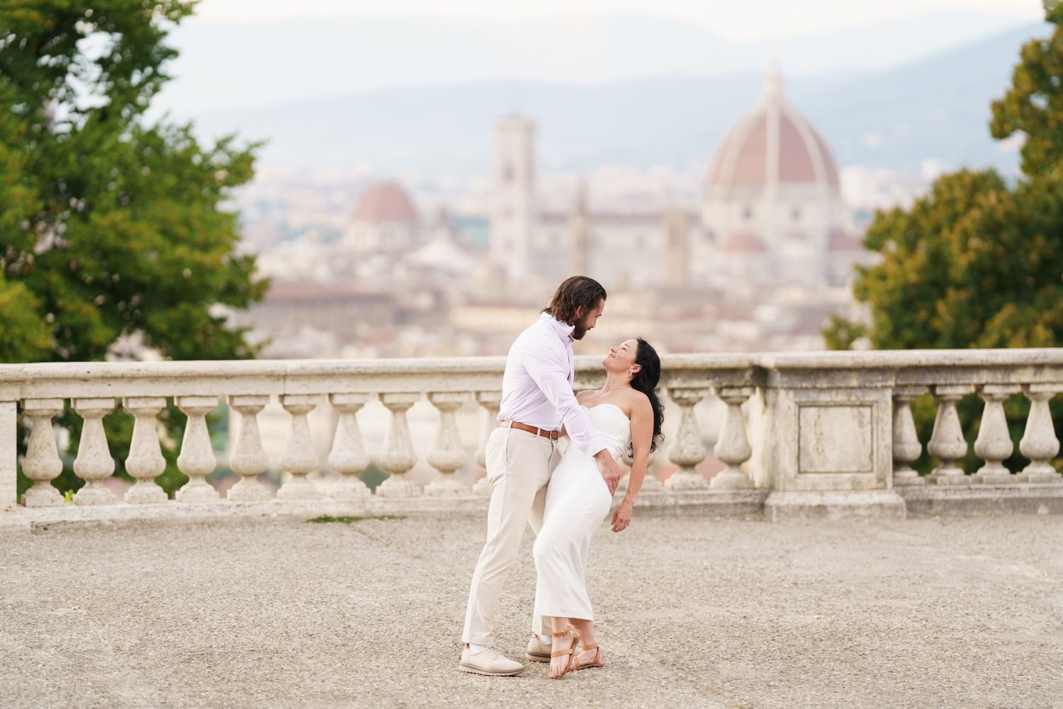 Romantic couple enjoying scenic views of Florence, Italy from Piazzale Michelangelo at sunset.