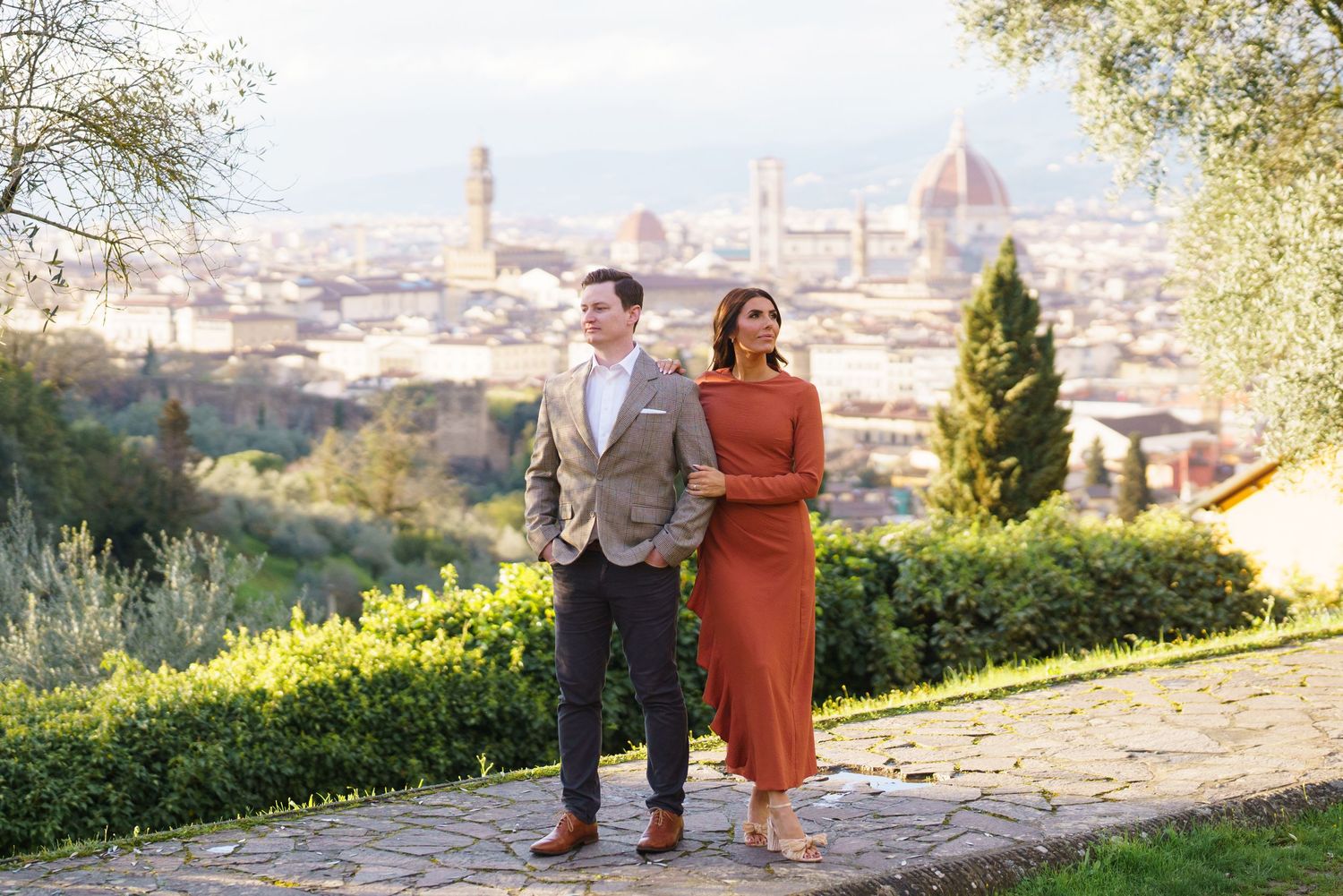 Couple posing with Florence skyline and Duomo cathedral backdrop during golden hour in Italy.