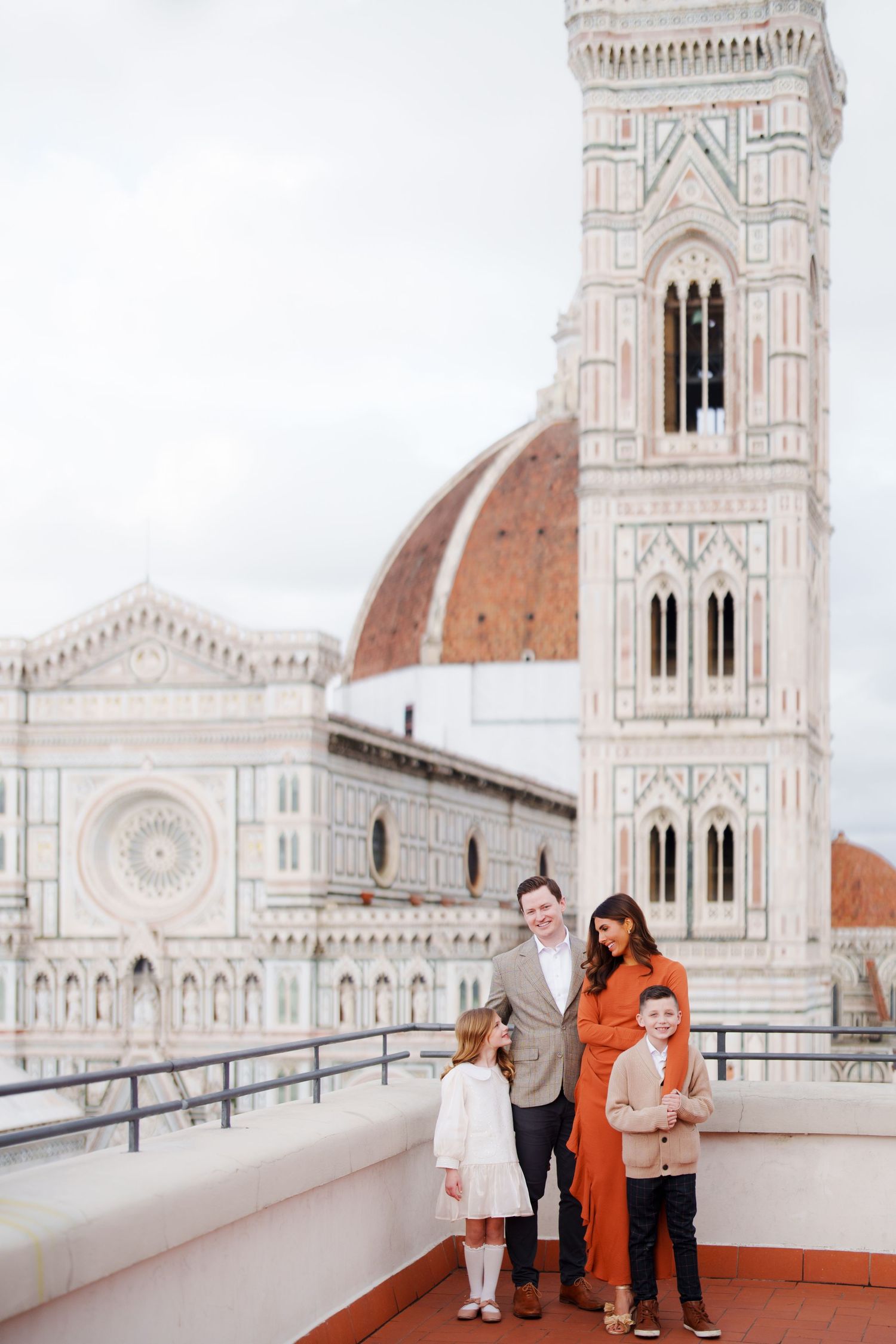 Family posing on a rooftop terrace with Florence Cathedral and Giotto's Campanile in the background, Italy.