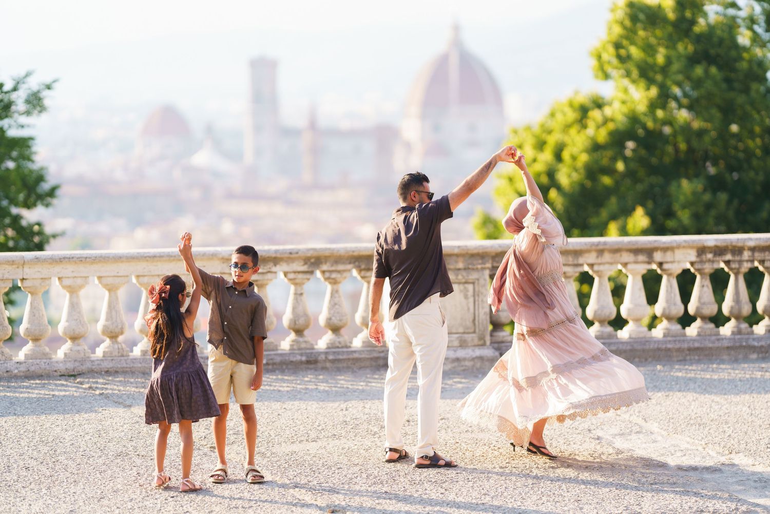 Family dancing joyfully on a terrace in Florence, Italy, with the iconic Duomo cathedral visible in the background.