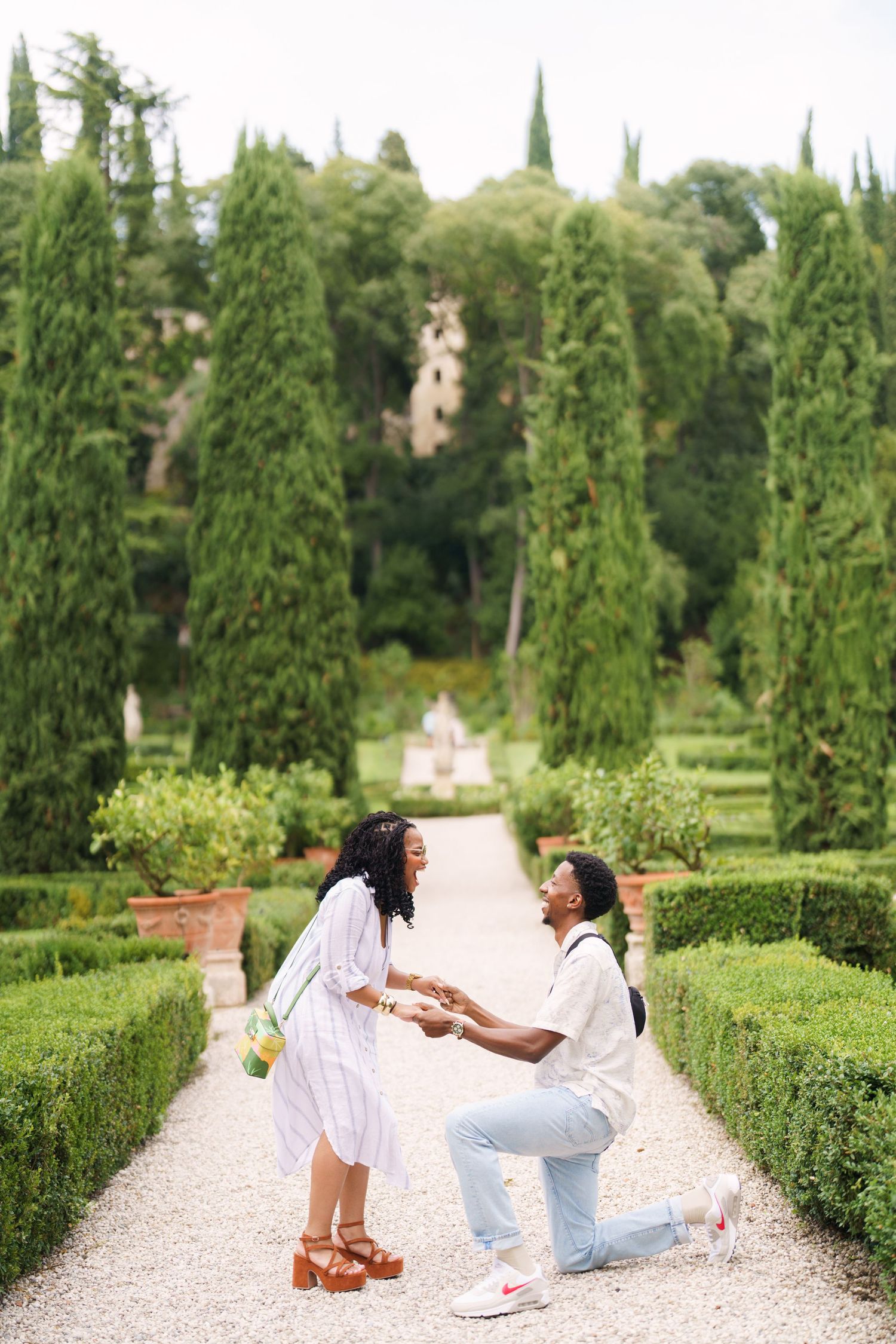 Man proposes on one knee to woman in elegant Italian garden Surprise engagement proposal in Verona captured in cinematic and elegant photogr