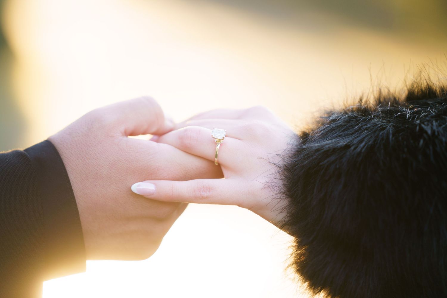Two hands reaching towards each other with sunlight glowing in the background during a tender moment.