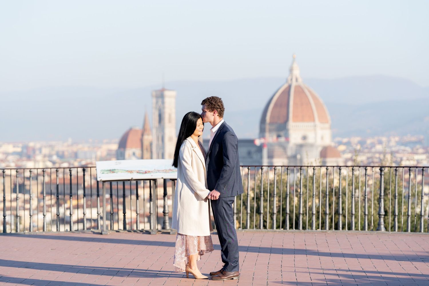 A couple shares a romantic moment overlooking the historic skyline of Florence, Italy from Piazzale Michelangelo.