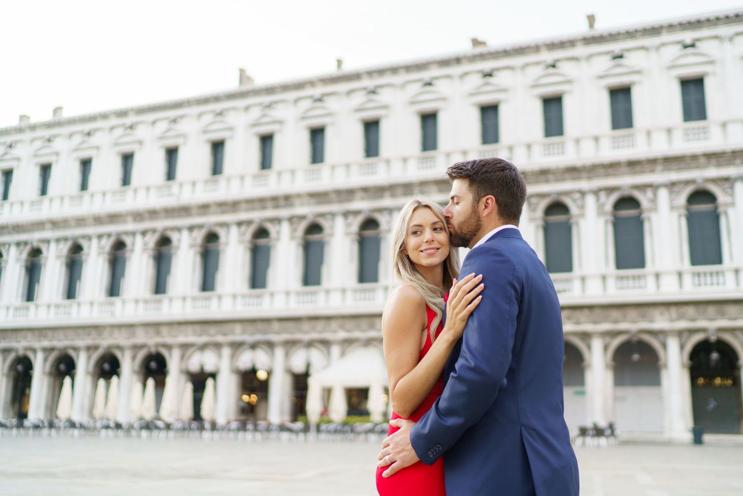 A couple embraces in front of the historic St. Mark's Square in Venice, Italy during a romantic photoshoot.