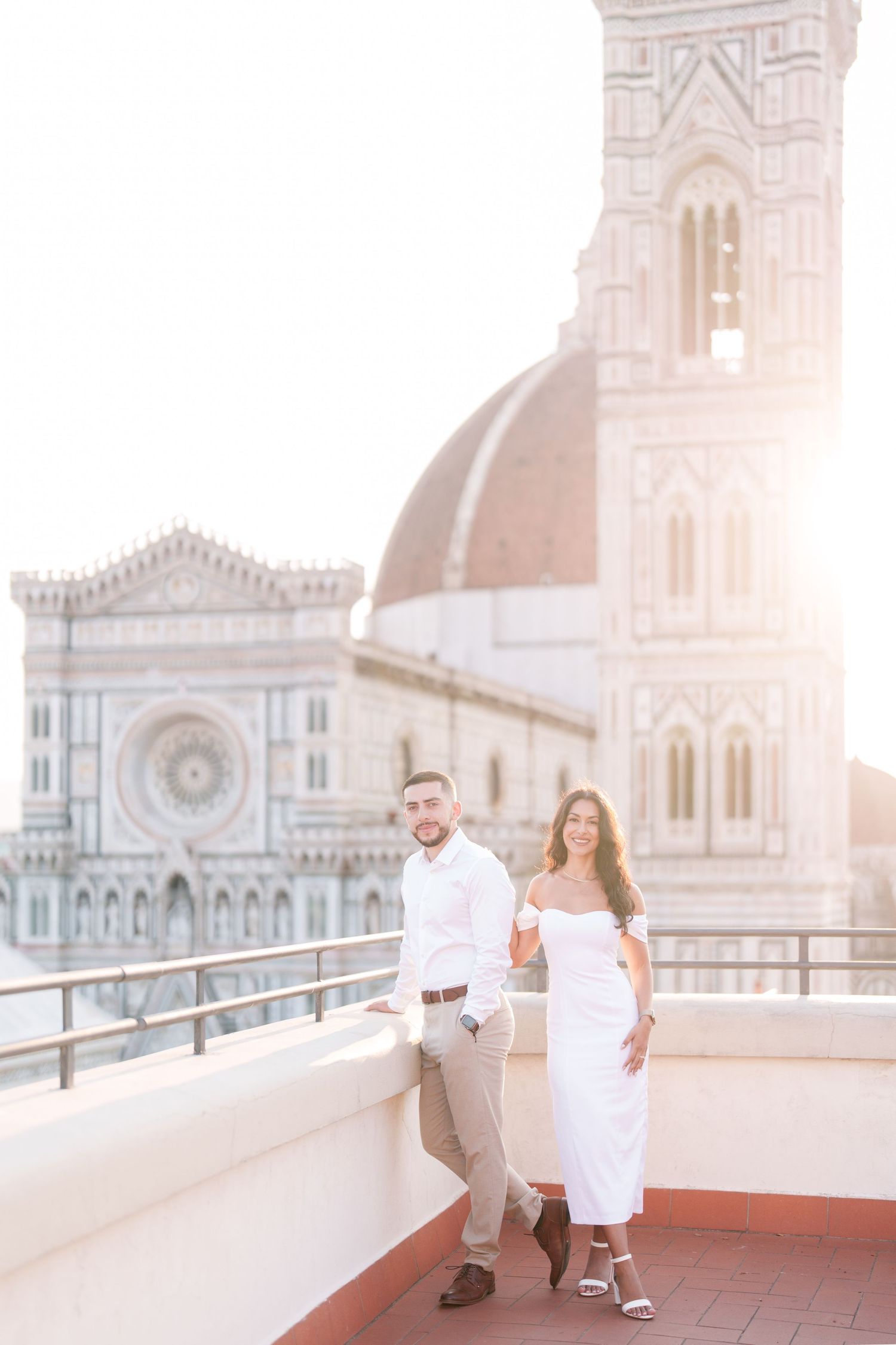A couple shares romantic moments at sunset on a rooftop terrace overlooking Florence Cathedral in Italy.