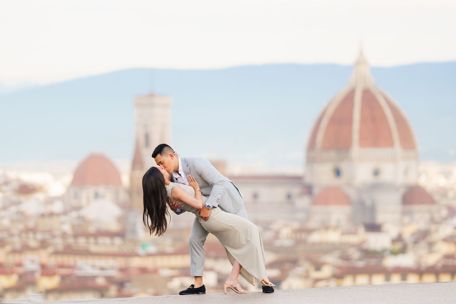 A romantic couple embraces against the stunning backdrop of Florence, Italy with the iconic Duomo cathedral in view.