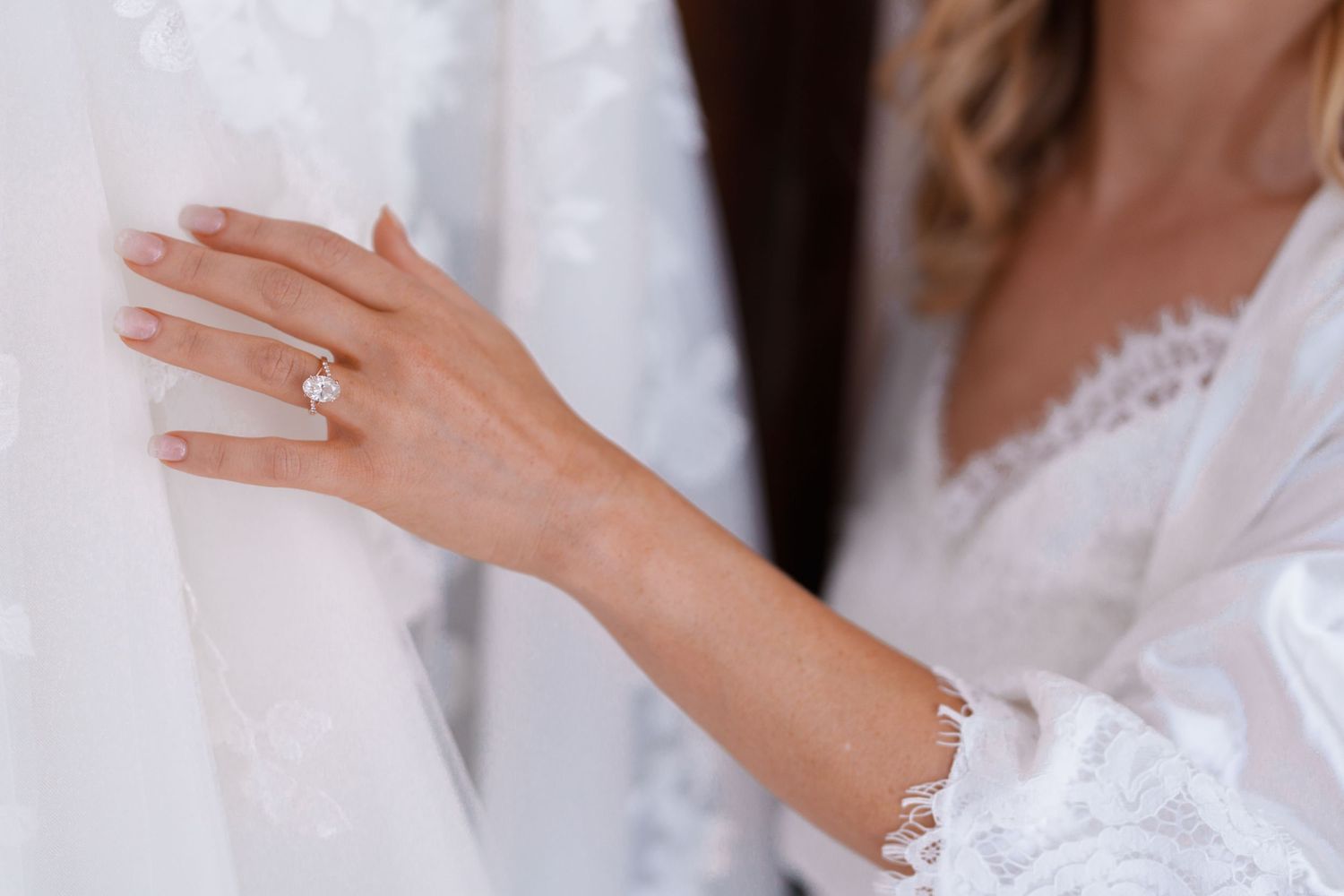Close-up of engagement ring and lace sleeve details.